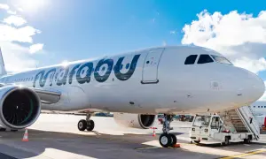 Ein weißes Flugzeug der Marabu Airlines steht am Flughafen. Die Sonne scheint auf den Rumpf, und eine Treppe ist am Eingang angebracht.
