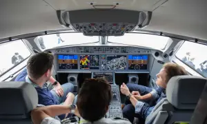 Einblick ins Cockpit: Drei Männer blicken auf die Instrumente, während sie im Flugzeug mitfliegen.