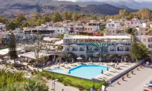 Ein **epos luxury beach hotel** mit Pool und Liegestühlen, umgeben von mediterraner Vegetation und Häusern, im Hintergrund Berge.