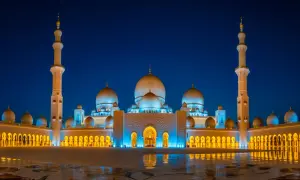 Die Sheikh-Zayid-Moschee in Abu Dhabi erstrahlt nachts in blauem und goldenem Licht.