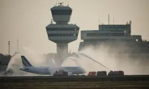 Air France Flugzeug wird auf dem Rollfeld der Berlin Airports mit Wasser begrüßt. Der Kontrollturm und das Terminal sind im Hintergrund zu sehen.