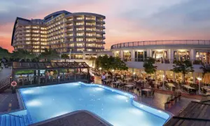 Abendstimmung am Pool des Liberty Lara Hotels. Gäste genießen das Abendessen im Freien unter dem farbenprächtigen Himmel.