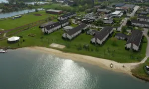 Luftaufnahme des Wangerland Resorts mit Gebäudekomplexen, einem See und einem Strand.