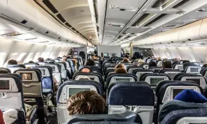Blick in die Kabine eines Flugzeugs mit vielen Reihen von Langstreckenflug Sitzen, einige mit Bildschirmen.