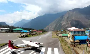 Ein kleines Flugzeug steht auf dem Rollfeld des Nepal Flughafens, umgeben von majestätischen Bergen.