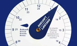 Eine Parkscheibe zeigt die Ankunftszeit. Man muss die Parkscheibe aufrunden, um die erlaubte Parkdauer einzuhalten.