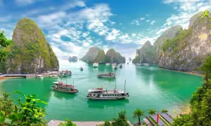 Traumhafte asien reiseziele: Boote gleiten durch smaragdgrünes Wasser, umgeben von steilen, bewachsenen Karstfelsen im Halong-Bucht.