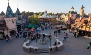 Bunte Märchenhäuser und ein Karussell beleben den Platz. Eine lebhafte Menge schlendert umher, perfekt für die Disneyland-Packliste.
