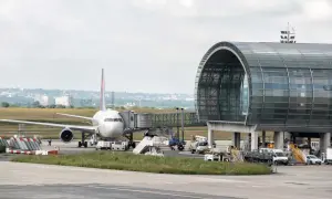 Flugzeug am Gate mit modernem Terminalgebäude. Die Frage "paris welcher flughafen am besten" wird hier nicht beantwortet, aber die Szene zeigt einen belebten Flughafen.