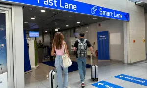 Paar geht zur flughafen sicherheitskontrolle. Ein Schild weist auf die "Fast Lane" und "Smart Lane" hin.
