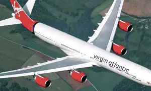 Ein Airbus A340-600 der Virgin Atlantic Flotte fliegt über grüne Landschaften.