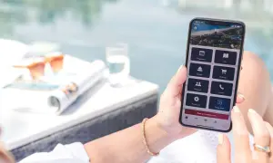 Frau nutzt Handy-App, um eine TUI Reise zu stornieren. Auf dem Bildschirm sind Optionen wie "Bookings" und "Change hotel" sichtbar.