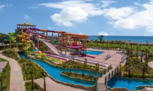 Ein riesiger Wasserpark mit bunten Rutschen, einem Lazy River und Pools. Das Meer im Hintergrund. Ein delphin be grand Urlaubstraum.
