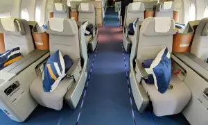 Lufthansa Business Class Sitze mit blauen Kissen und Decken. Ein Blick in den Gang, der Hoffnung auf einen Standby-Ticket-Lufthansa-Traumflug macht.