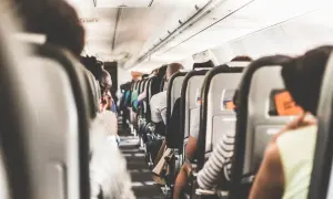 Blick in die enge Flugzeugkabine, wo die Sitze dicht an dicht stehen. Ein Gefühl von Platzangst im Flugzeug kann aufkommen, wenn man die vielen Passagiere sieht.