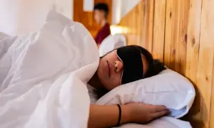 Frau schläft mit Schlafmaske, um Jetlag zu bekämpfen. Die Richtung des Jetlags ist egal, Hauptsache Schlaf.