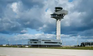 Moderner flughafen tower mit Glasfronten und einem Betonpfeiler, der über das Rollfeld ragt.