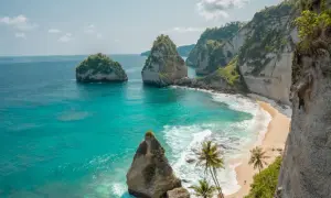 Traumhafter Urlaub auf Bali: Türkisblaues Meer trifft auf einsame Sandstrände und steile Felsklippen mit Palmen. Ein Paradies!