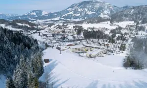 Winteridylle am Robinson Fieberbrunn: Hotelanlage mit Skilift und verschneiten Bergen im Hintergrund.