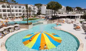 Bunte Wasserrutsche im Pool des Viva Cala Mesquida Resort & Spa. Kinder planschen im Wasser.