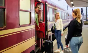 Junge Leute mit Gepäck steigen in den Zug für ihre TUI Bahnreise.