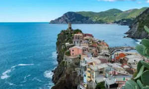 Bunte Häuser kleben an steilen Klippen am Meer. Ein perfekter Urlaub in Italien, mit Blick auf das azurblaue Meer und die Berge.
