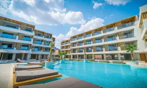 Entspannter Urlaub im Akasha Beach Hotel & Spa: Moderne Architektur, ein einladender Pool und Liegen unter blauem Himmel.