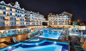 Nachtansicht des Diamond Beach Hotel & Spa mit beleuchteten Pools, Rutschen und Liegestühlen.
