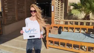 Frau in Hurghada Kleidung, mit Sonnenbrille, hält ein Schild von Peter Tours. Sie trägt Jeans und ein weißes Oberteil.