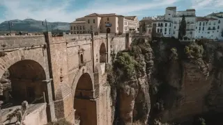 Majestätische Brücke in Ronda, Spanien, überspannt eine tiefe Schlucht. Weiße Häuser klammern sich an die Felsen.