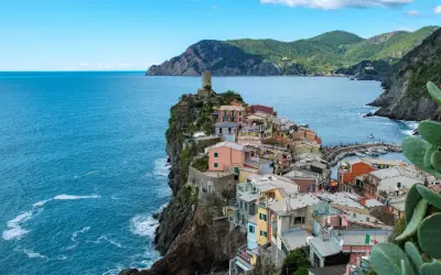 Bunte Häuser kleben an steilen Klippen am Meer. Ein perfekter Urlaub in Italien, mit Blick auf das azurblaue Meer und die Berge.