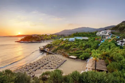 Sonnenuntergang am Club Marvy: Ein Strand mit vielen Liegen, ein Wasserpark und üppige Vegetation.
