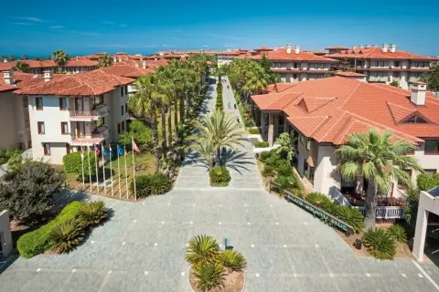 Blick auf das Club Grand Side Resort mit Palmen und roten Ziegeldächern.