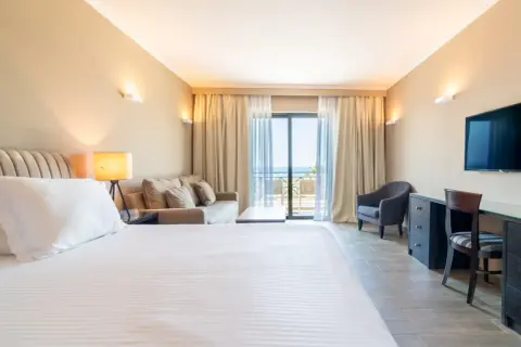 Gemütliches Zimmer im sentido pelagos suites & spa mit Meerblick vom Balkon. Einladendes Bett, Sofa und Schreibtisch.