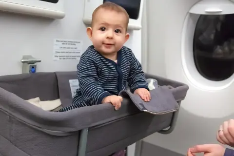 Kleines Baby in Flugzeug-Babywiege, der beste Sitzplatz im Flugzeug mit Kleinkind für eine entspannte Reise.