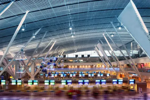 Moderne Flughafenhalle mit vielen Check-in-Schaltern, die für das standby fliegen bereit sind. Die geschwungene Decke und die stützenartige Architektur sind beeindruckend.