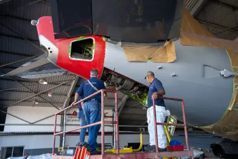 Zwei Mechaniker auf einer Hebebühne arbeiten am Triebwerk eines Flugzeugs. Ein wichtiger Begriff aus der Fliegerei wird hier greifbar.