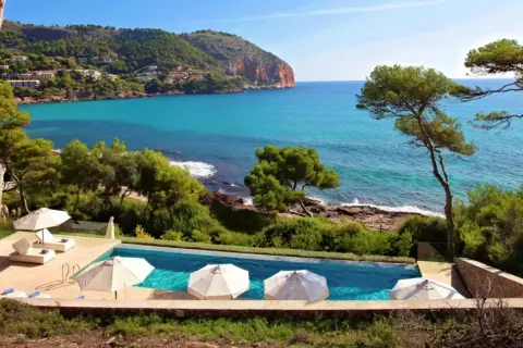 Traumhafter Poolblick auf das Meer bei Simoneta Mallorca. Sonnenschirme und Liegen laden zum Entspannen ein.