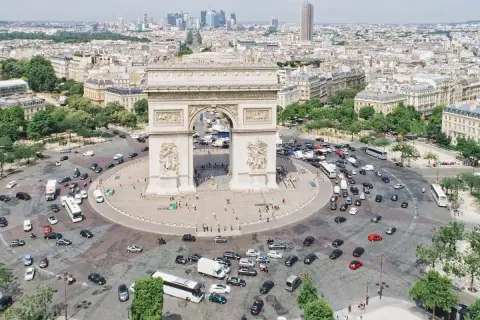 Ein Auto fährt durch Paris, vorbei am Triumphbogen. Die Skyline von Frankfurt ist in der Ferne zu sehen.