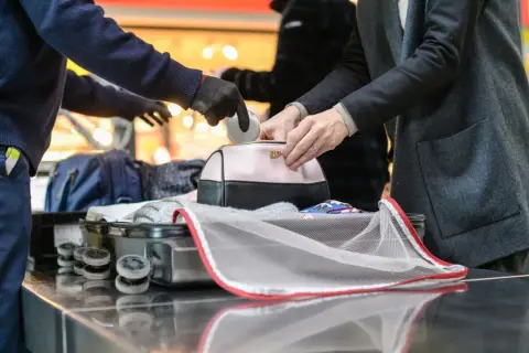 Sicherheitskontrolle am Flughafen: Medikamente werden aus einer Kosmetiktasche genommen, bevor das Gepäck in den Flugzeug-Container kommt.
