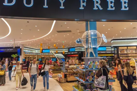 Menschen bummeln durch einen beleuchteten duty free Shop mit vielen Waren.