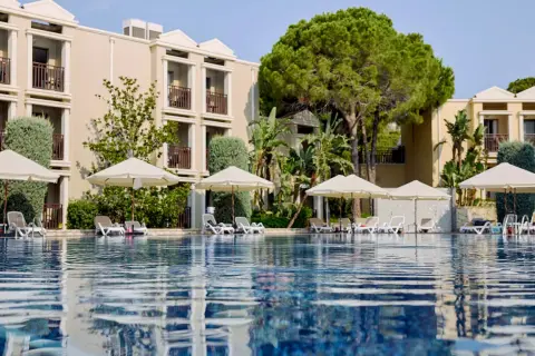 Ein Pool mit Liegen und Sonnenschirmen vor einem Hotelgebäude. Hier beginnt das magic life Belek.