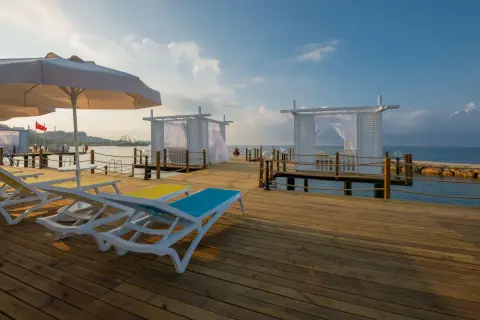 Sonnenliegen und weiße Pavillons auf einem Holzsteg am Meer, ein perfekter Ort für einen Urlaub im Mary Hotel Alanya.