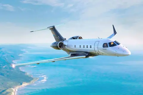 Ein modernes Privatflugzeug fliegt über dem Meer. Die Frage, wie viel kostet ein Passagierflugzeug, ist komplex, aber dieses Modell ist ein Luxusgut.