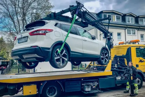 Ein weißer Nissan wird von einem Abschleppwagen in Frankfurt auf die Ladefläche gehoben. Die Abschleppkosten sind hier wohl im Service enthalten.