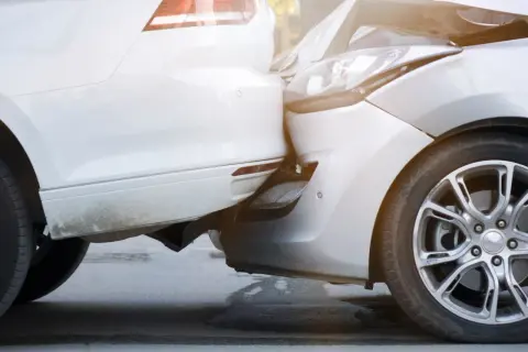 Zwei Autos sind kollidiert, ein weißes und ein silbernes. Der Unfall beim Ausparken hat die Stoßstangen und Scheinwerfer beschädigt.