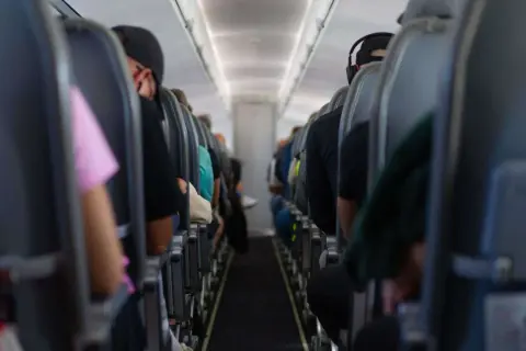 Blick in die Kabine eines Flugzeugs mit Passagieren auf ihren Sitzen. Die Wahrscheinlichkeit eines Flugzeugabsturzes ist extrem gering, aber die Enge hier lässt einen über alles nachdenken.