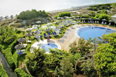 Einladende Pools und Liegen am Strand des Grupotel Natura Playa. Sonnenschirme spenden Schatten.