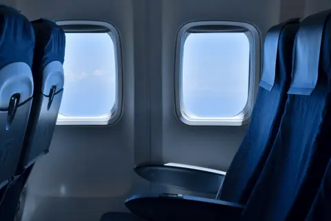 Leere Flugzeugsitze mit Blick auf den blauen Himmel. Eine Sitzplatzreservierung im Flugzeug ist sinnvoll, um den besten Platz zu sichern.