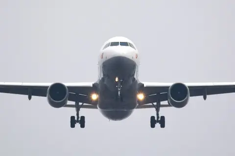 Ein Flugzeug nähert sich mit hoher Geschwindigkeit der Landebahn. Die Lichter am Fahrwerk leuchten hell.